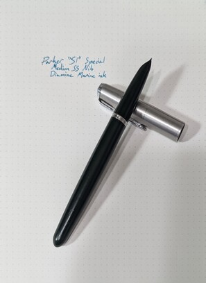 Photato of my Parker 51 Special, in Forest Green colorway, on top of a dot-grid notebook with 'Parker 51 Special, Medium SS Nib, Diamine Marine ink' scrawled above it on the paper in blue-green.